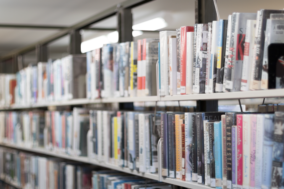 Warm library bookshelf filled with various books, captured in ambient light.