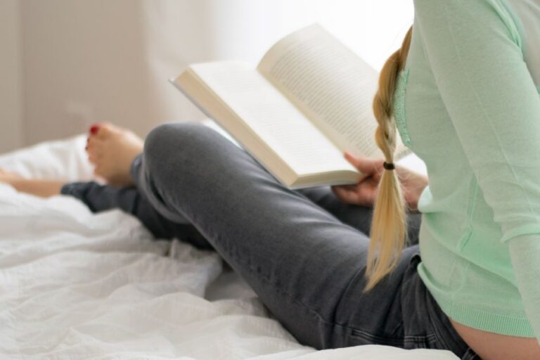 Woman relaxes while reading a book in a cozy indoor setting, exuding tranquility.