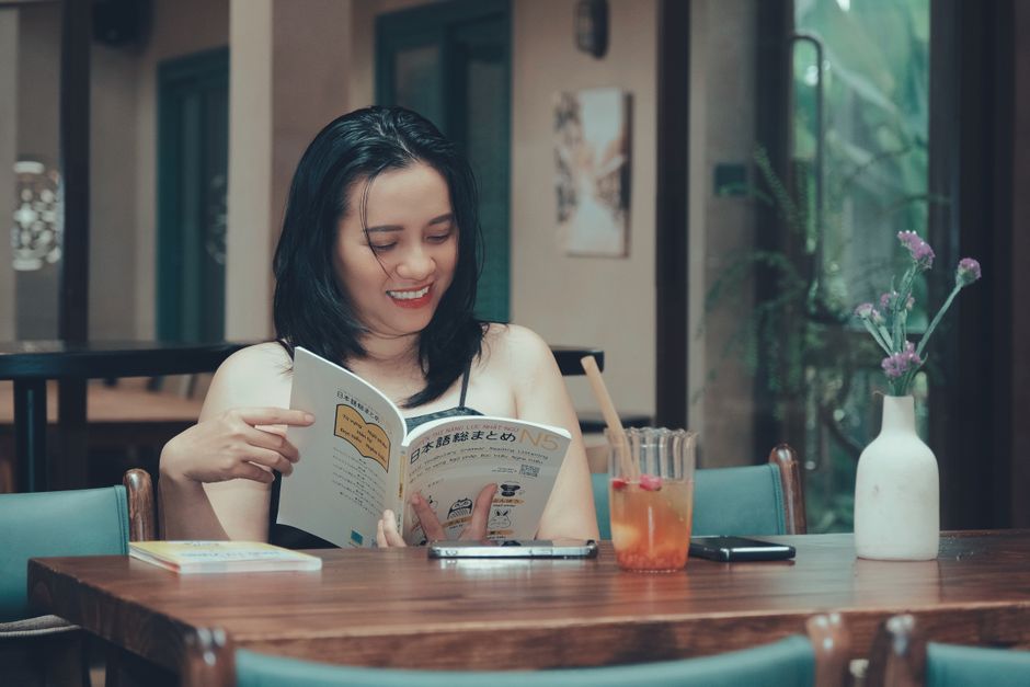 Woman relaxes while reading a book in a cozy indoor setting, exuding tranquility.
