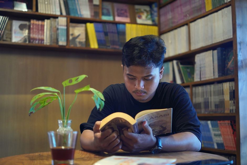 A warm library setting with filled bookshelves and a coffee cup on the table.