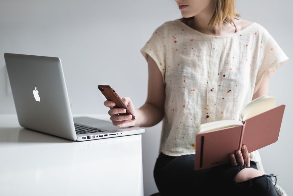 Focused pleasant female in casual outfit studying interesting novel on couch with cushion near window