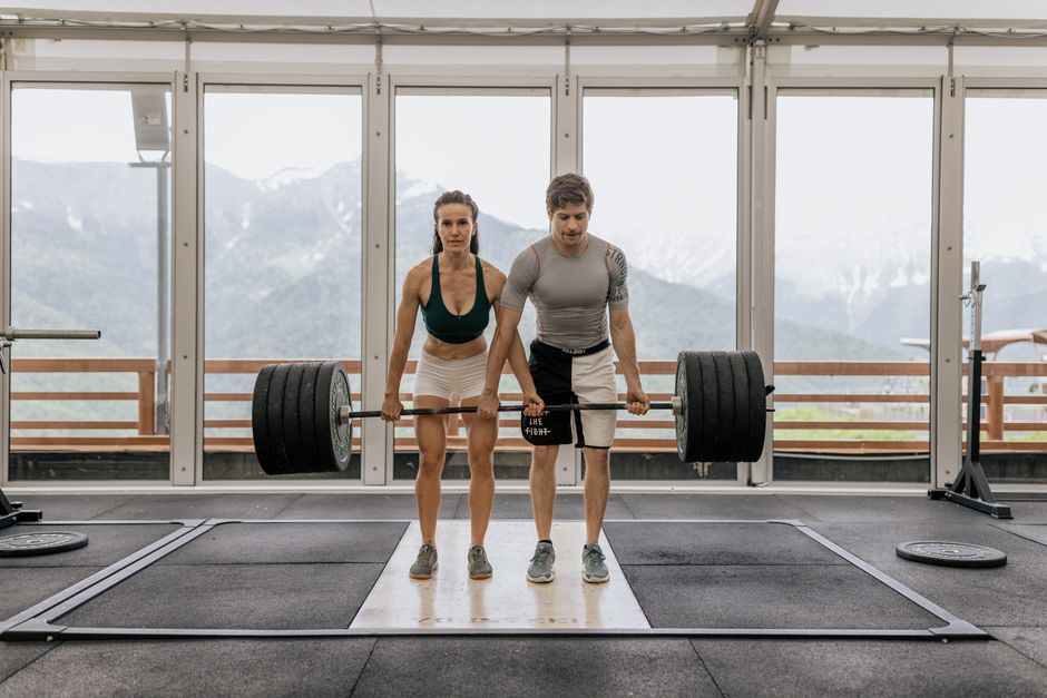 Three adults exercising with dumbbells in a gym setting, promoting fitness and healthy lifestyle.