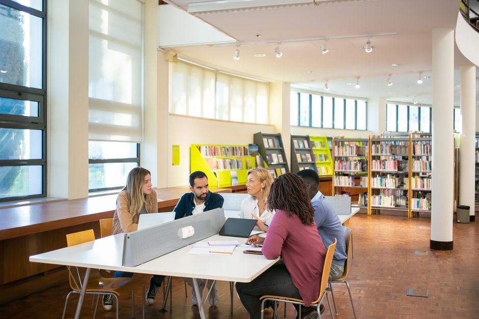 A young woman wearing glasses browses books in a well-lit library, symbolizing education and self-improvement.
